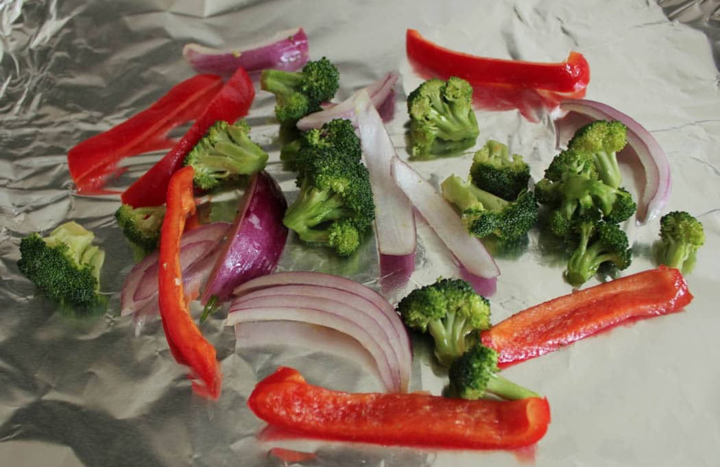 Vegetables with olive oil and seasoning ready to be roasted for cauliflower pizza crust