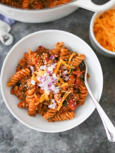 Bowl of one-pot cheeseburger pasta with toppings.
